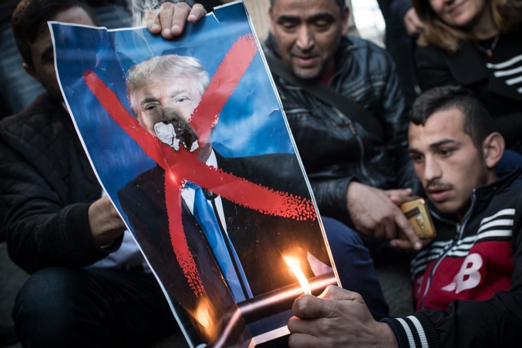Protesters burning a poster of President Donald Trump