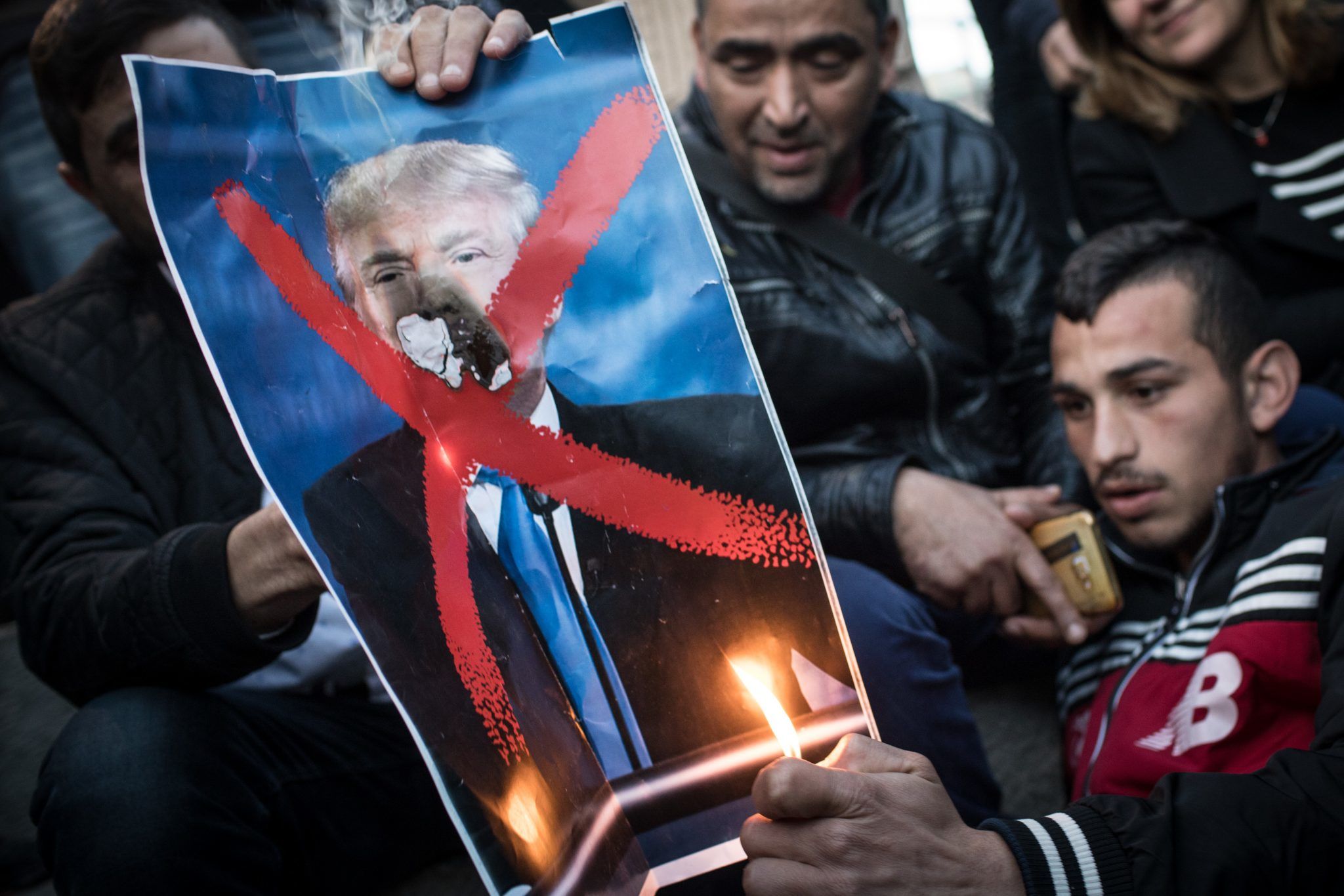 Protesters burning a poster of President Donald Trump
