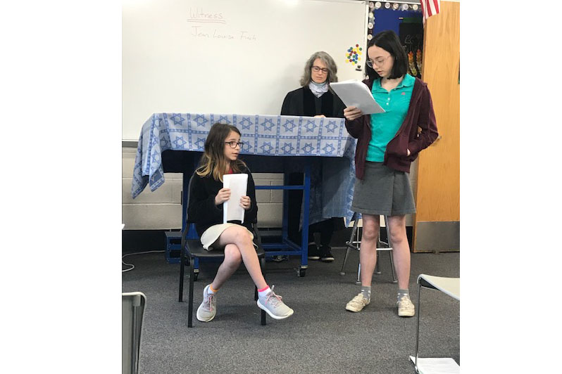 Hannah S., Jenna N., and teacher Ms. Kelly Platzke participate in a mock trial.