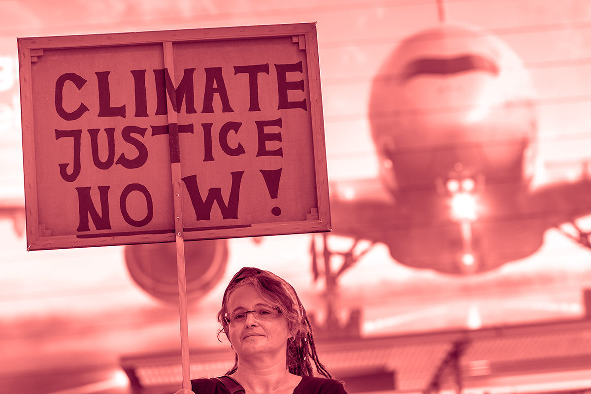 Woman holds "Climate Justice Now" sign. (Photo by PETER KNEFFEL/AFP/Getty Images)