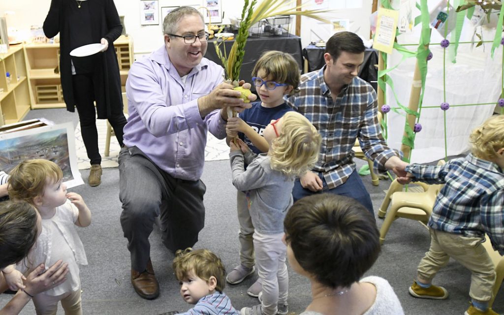 Rabbi Etan Mintz helps children shake lulov and etrog during the "Sukkot Under the Stars" event at Beth El preschool in Federal Hill. (Photo by Steve Ruark)
