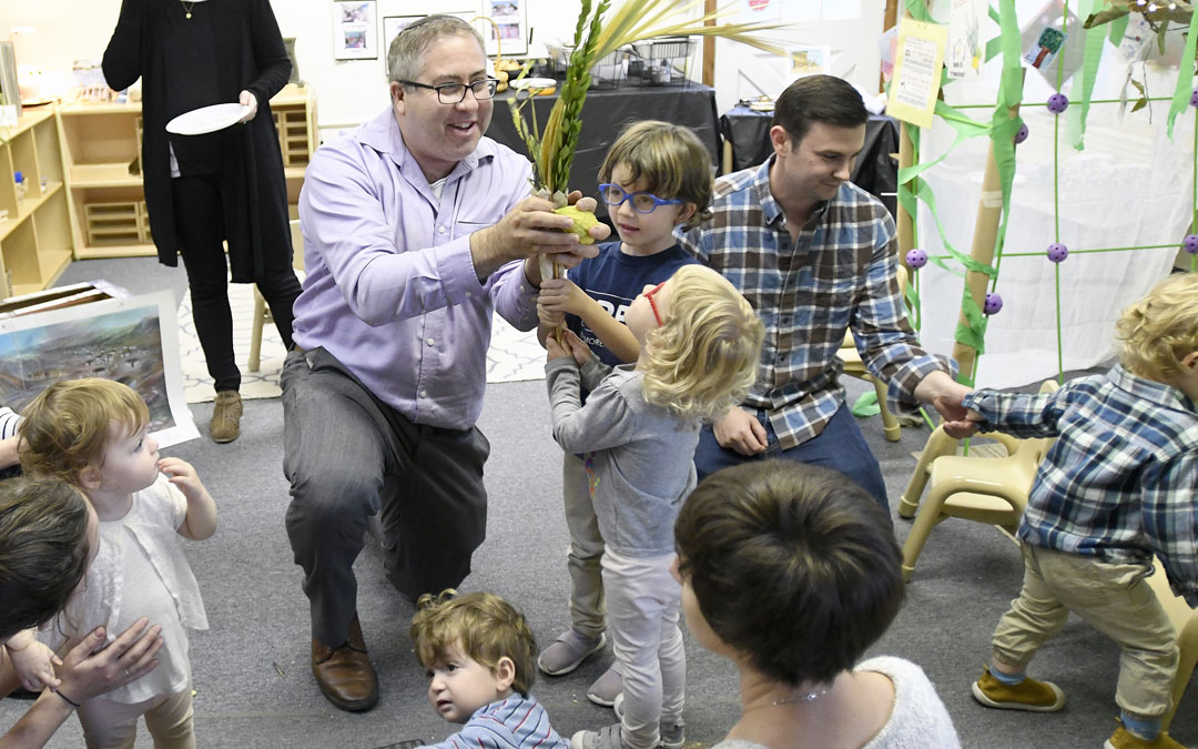Rabbi Etan Mintz helps children shake lulov and etrog during the "Sukkot Under the Stars" event at Beth El preschool in Federal Hill. (Photo by Steve Ruark)