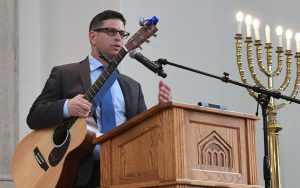 Rabbi Daniel Cotzin Burg talks to the Beth Am audience before playing his guitar. (Photo by Jim Burger)