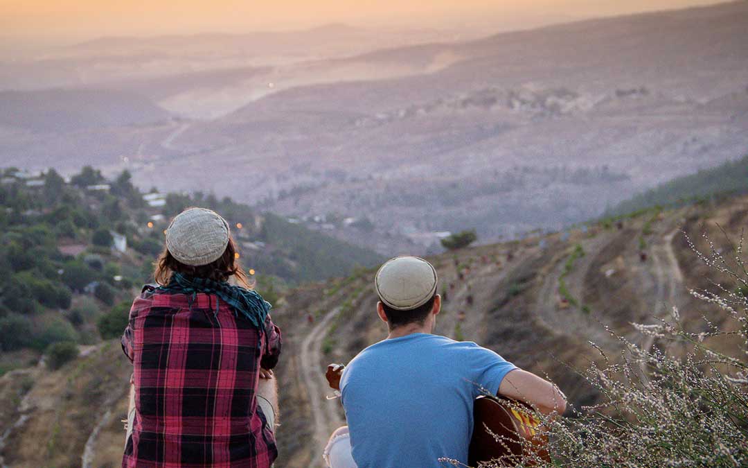 A pair of Jewish youngsters watch a sunset from the West Bank. (Photo by Laura Ben-David)