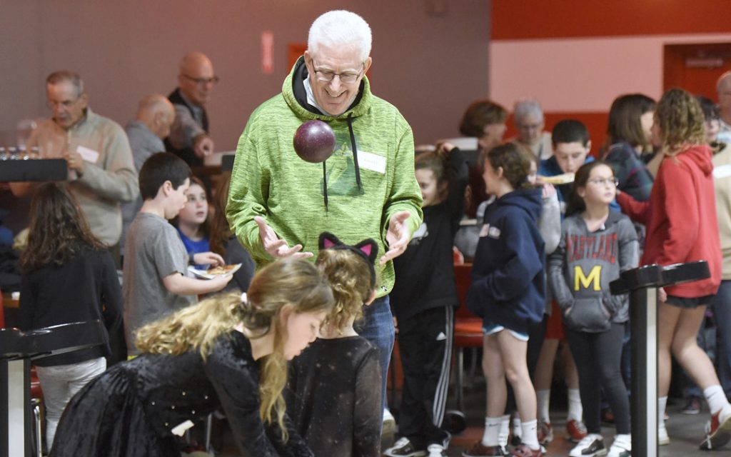 Richard Friedlander, of Pikesville, shows off for his granddaughter Anna Galiatsatos, 6, of Pikesville, during the Macks Center for Jewish Education's Saba-ba: Grandparents on the Go launch party at AMF Pikesville Lanes. The Saba-ba program brings together children and their grandparents. (Photo by Steve Ruark)
