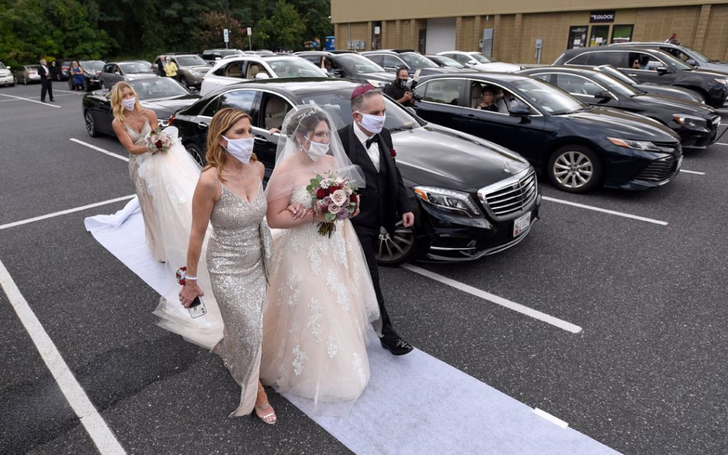 In the parking lot of the Horizon Cinemas Fallston, the bride is walked down the aisle by her parents.