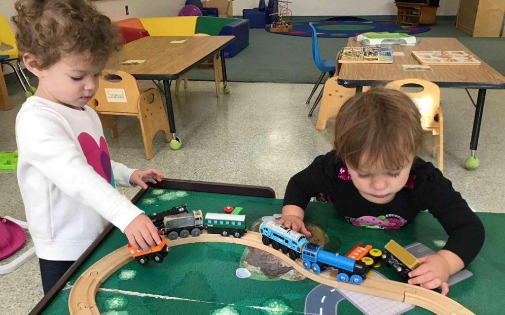 Toddlers navigating the busy train table.