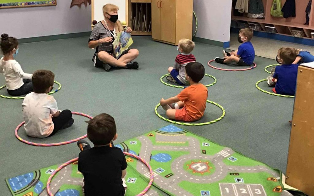 Children in the three-year-old class sitting safely apart for story time.