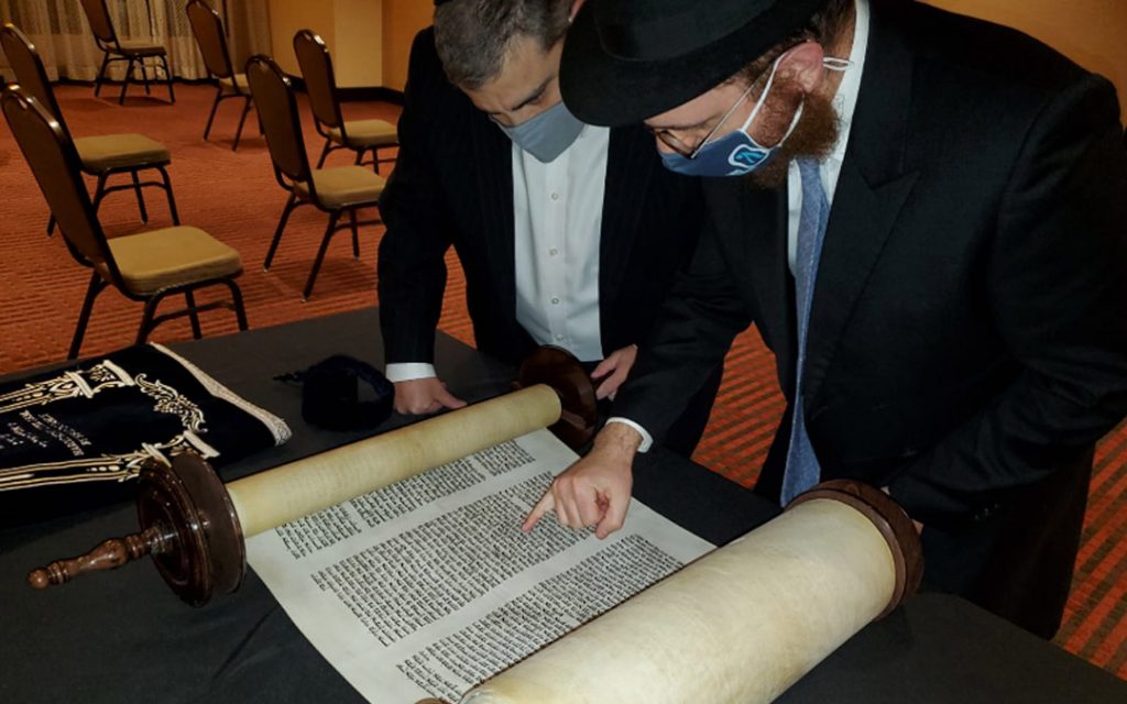 Rabbi Levi Druk (right) and Elton Juter inspect the new Torah. (Photo by Naftali Druk, Chabad of Downtown)