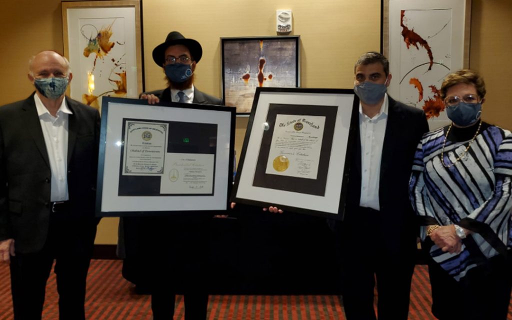 Rabbi Levi Druk and the Juter family hold up a proclamation issued by Gov. Larry Hogan in h honor of the new Torah. (Photo by Naftali Druk, Chabad of Downtown)