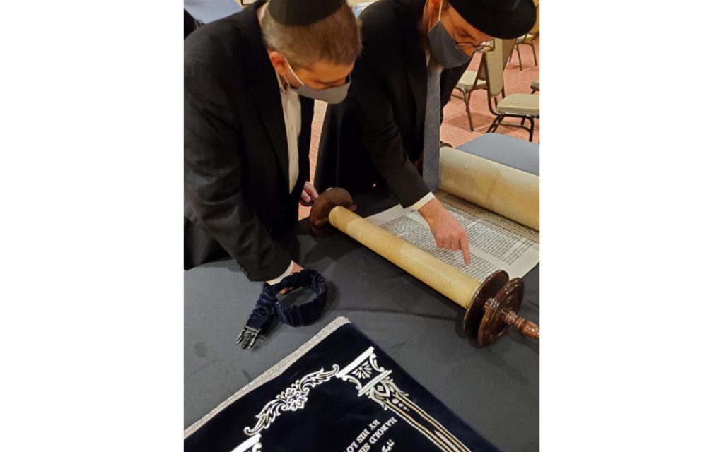 The new Harold Juter Torah is inspected carefully by Rabbi Levi Druk (right) and Elton Juter. (Photo by Naftali Druk, Chabad of Downtown)