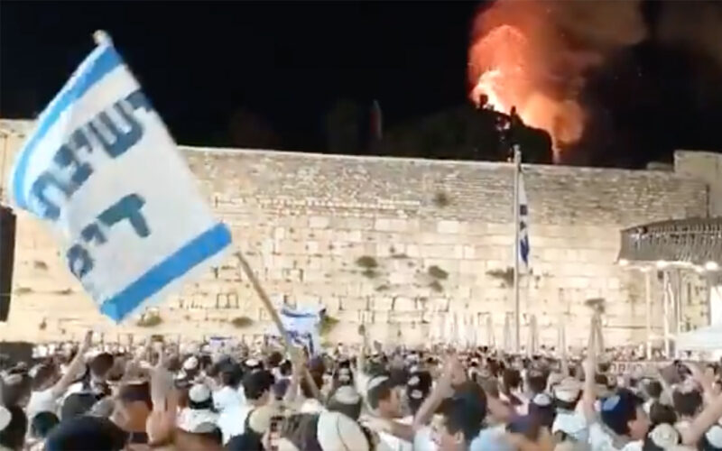 Israeli men at the Western Wall in Jerusalem sing and dance as they watch a fire burn outside the Al-Aqsa Mosque.