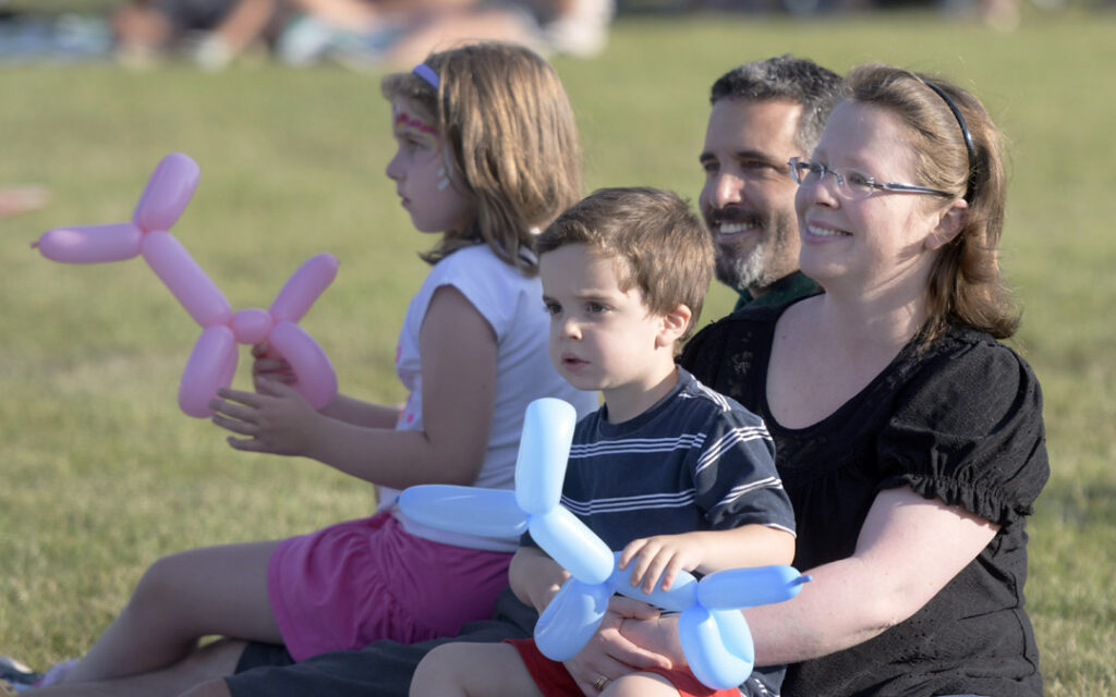 The Rabinovich family, from left, Vered, 7, Ethan, 3, Roye and Orna, of Owings Mills, listen to the rock music of Shrink the Deficit during Chizuk Amuno Congregation's SummerFest.