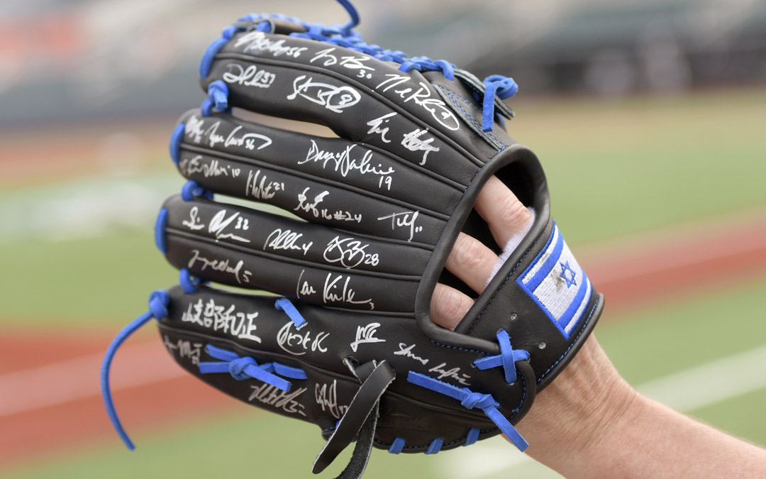 A supporter of Team Israel holds a baseball glove signed by many members of the team. (Photo by Steve Ruark)
