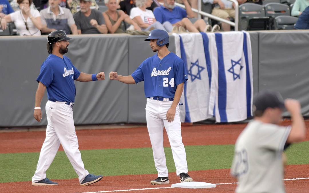 Team Israel's Assaf Lowengart (#24) fist bumps third base coach Nate Fish during an exhibition game against the Cal Ripken Collegiate All-Stars in Aberdeen. (Photo by Steve Ruark)