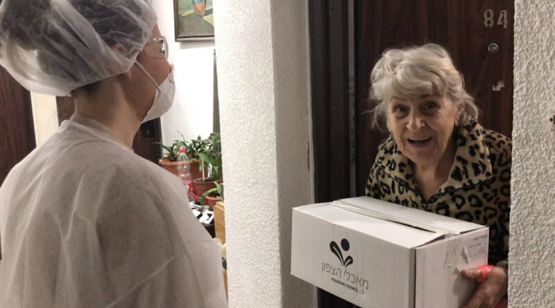 Employees from the Israel Electric Corporation deliver boxes of fresh fruit and vegetables to Holocaust survivors living in government-subsidized housing in the Haifa area.