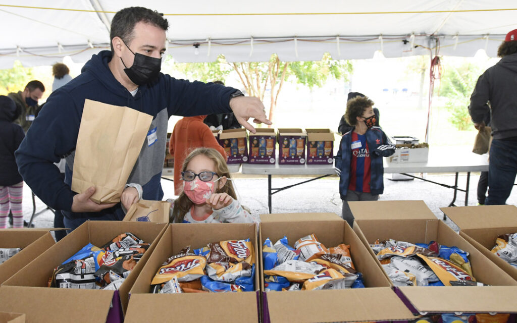 Michael Pachino and his daughter Winnie, 6, pack lunches for people facing food insecurity during Posner JEM Religious School's family education event to support JVC's Bunches of Lunches program.