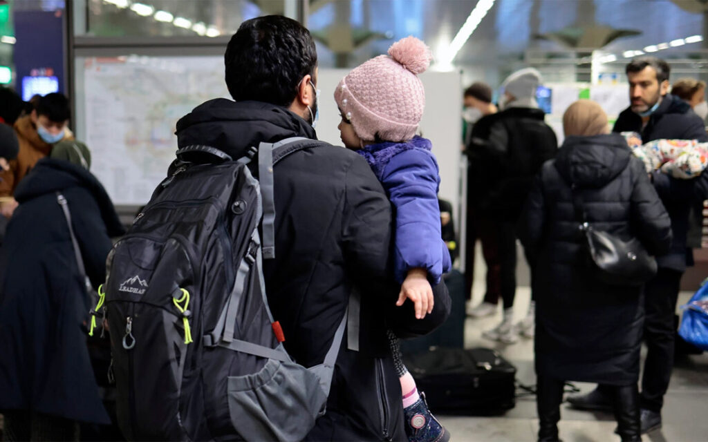 A man carries a child after refugees from Ukraine arrive at the main train station in Berlin