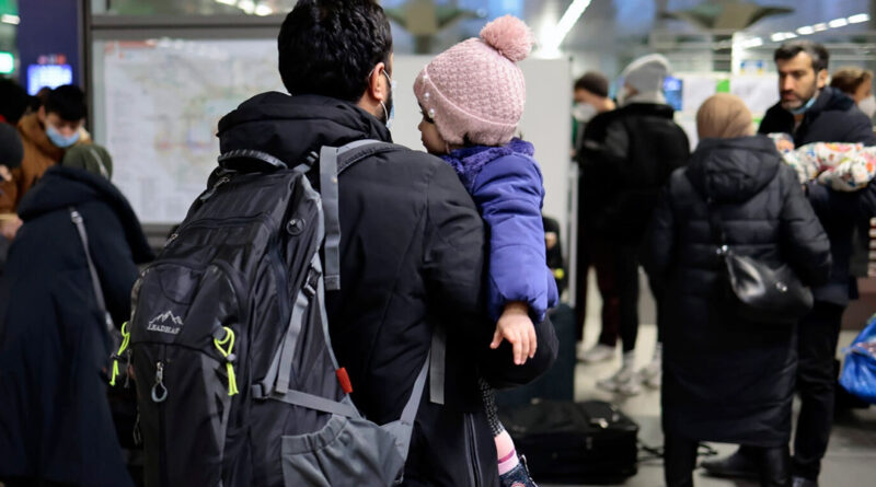 A man carries a child after refugees from Ukraine arrive at the main train station in Berlin
