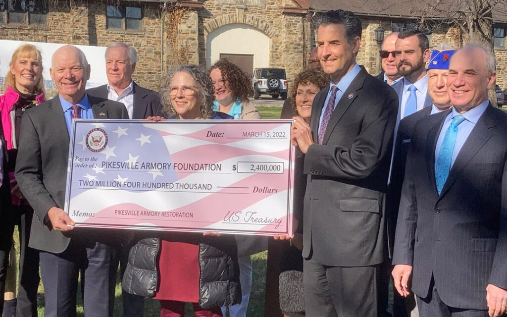 Representing the federal government, Sen. Benjamin L. Cardin (left) and Rep. John Sarbanes (right) present a ceremonial check for $2.4 million to the Pikesville Armory Foundation.