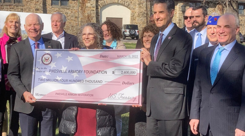 Representing the federal government, Sen. Benjamin L. Cardin (left) and Rep. John Sarbanes (right) present a ceremonial check for $2.4 million to the Pikesville Armory Foundation.