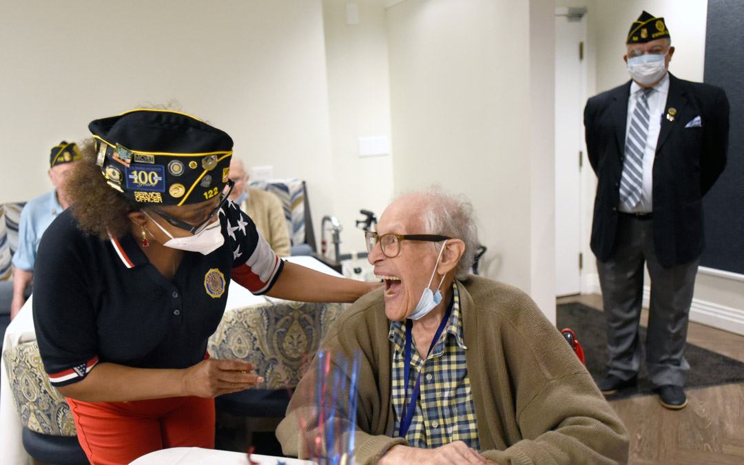 U.S. Army veteran Vanessa Deal (left), a service officer with American Legion Post 122, shares a laugh and presents a pin to U.S. Air Force veteran David Rosenberg, a World War II vet.