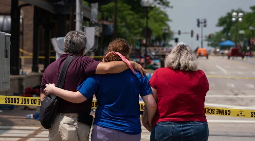 A family embraces while observing the scene of a mass shooting at a July 4th parade in downtown Highland Park, Illinois.
