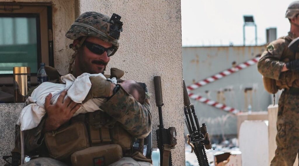 Sgt. Matt Jaffe, a U.S. Marine, holds a baby during an evacuation at Hamid Karzai International Airport in Kabul, Afghanistan, in August of 2021.