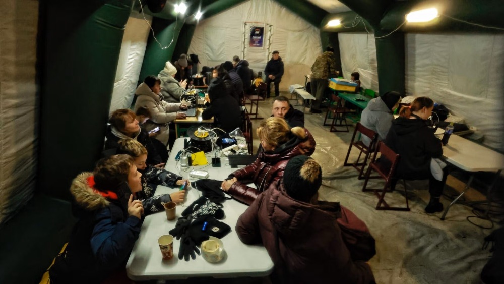 People charge their devices, eat and warm themselves at a mobile resilience hub in Kyiv, Ukraine