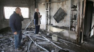 Palestinians inspect a burned-out house